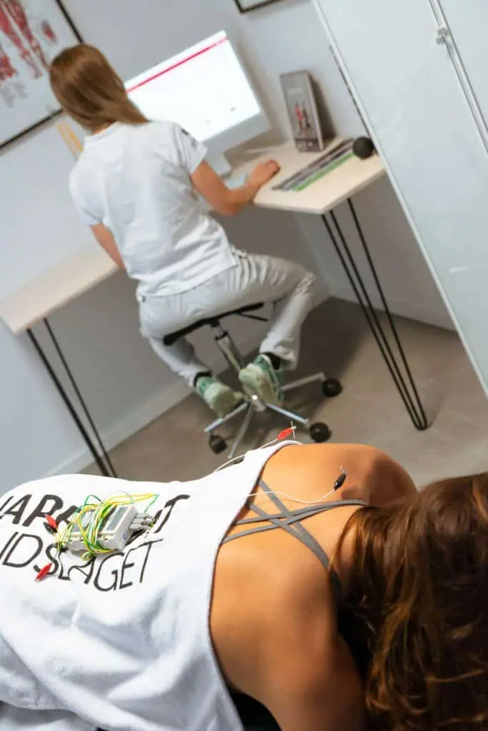 Therapist writing on a computer, patient laying on table